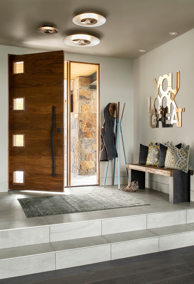 Esempio di un ingresso o corridoio minimal con pareti grigie, una porta singola, una porta in legno scuro e pavimento grigio