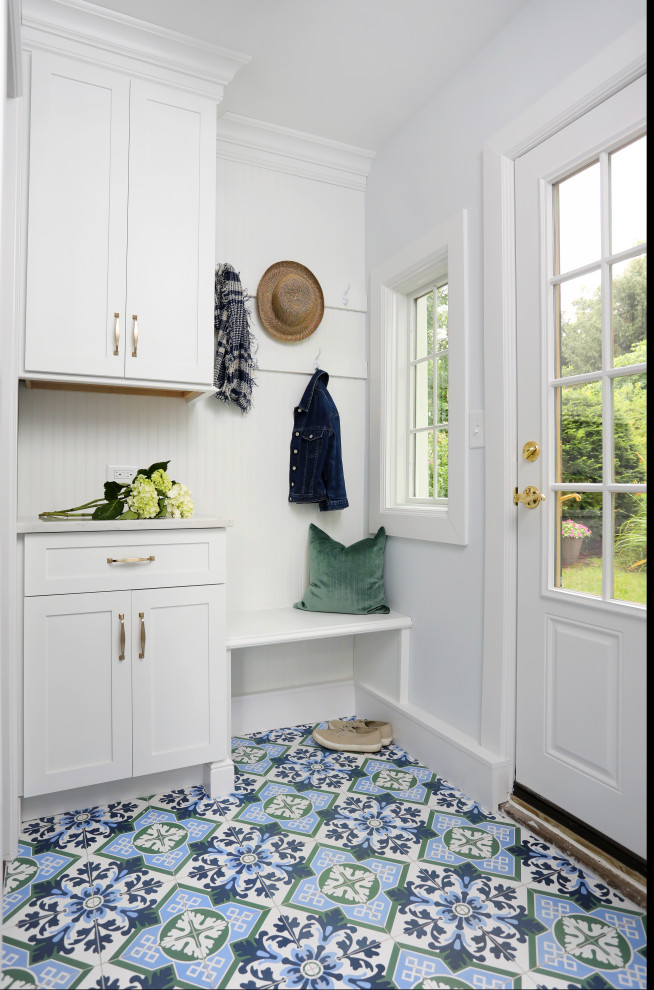 Cette image montre une petite entrée rustique avec un sol en carrelage de porcelaine, un vestiaire, un mur blanc, une porte simple, une porte blanche et un sol multicolore.
