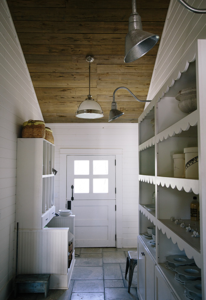 Lantlig inredning av ett kapprum, med vita väggar, en tvådelad stalldörr och en vit dörr