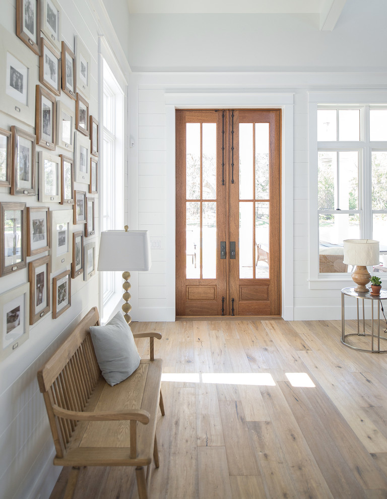 タンパにある高級な広いトランジショナルスタイルのおしゃれな玄関ロビー (白い壁、無垢フローリング、木目調のドア) の写真