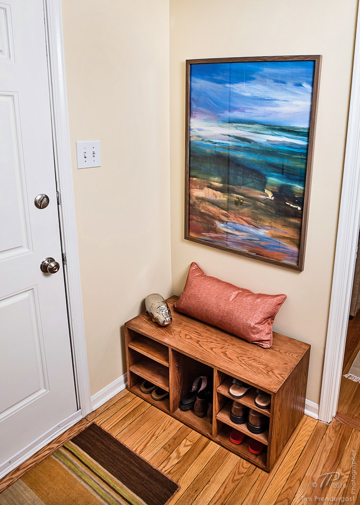 Example of a small minimalist light wood floor entryway design in Baltimore with yellow walls