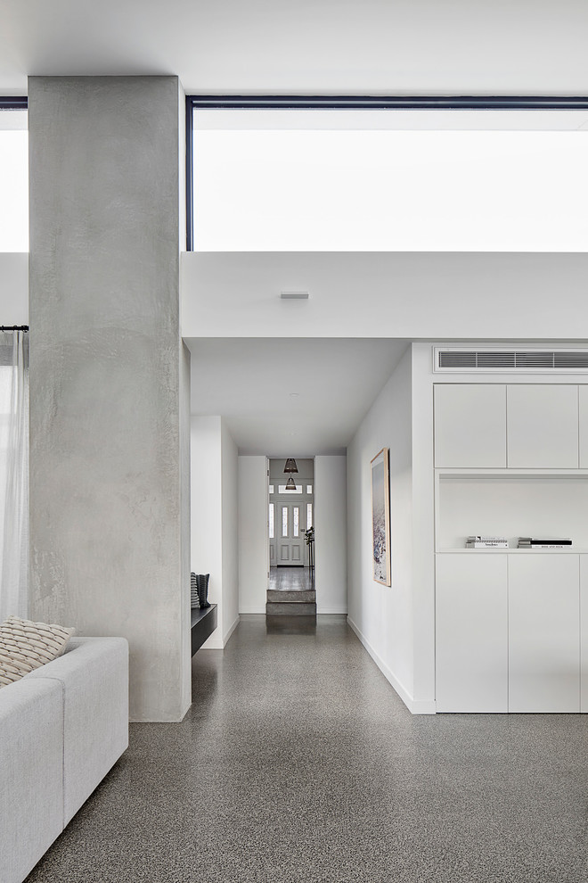 Foto di un grande corridoio minimal con pareti bianche, pavimento in cemento, una porta singola, una porta bianca e pavimento grigio