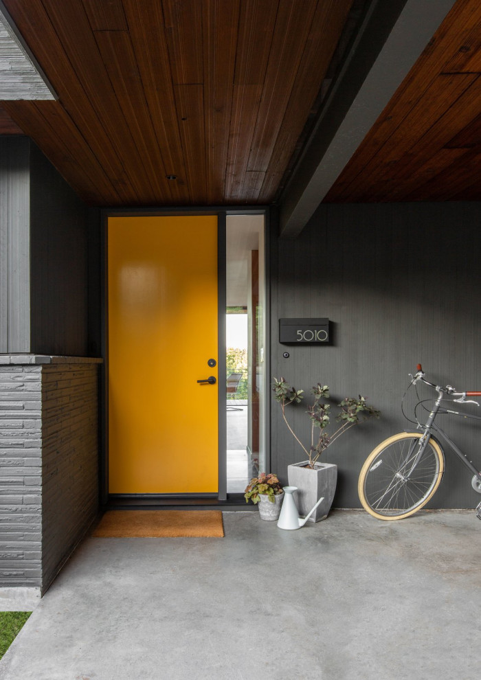 Modelo de puerta principal vintage de tamaño medio con paredes grises, suelo de cemento, puerta simple, puerta naranja y suelo gris