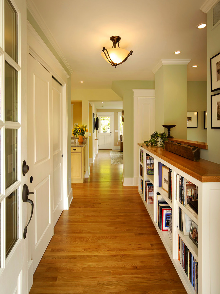 Ispirazione per un corridoio tradizionale di medie dimensioni con pareti verdi, pavimento in legno massello medio, una porta singola, una porta bianca e pavimento beige