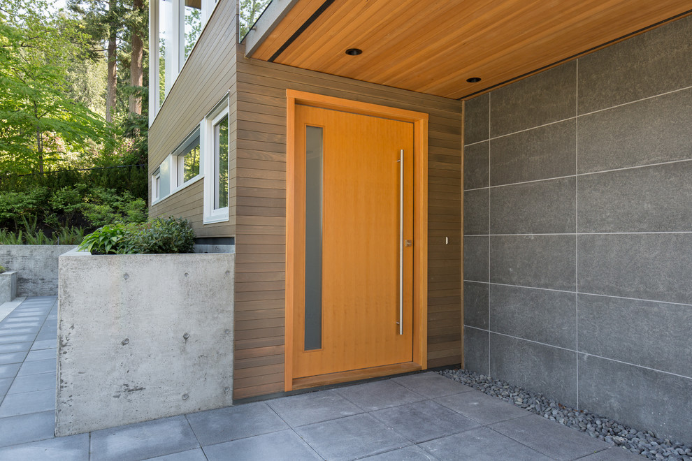 Example of a large minimalist gray floor entryway design in Vancouver with gray walls and a medium wood front door