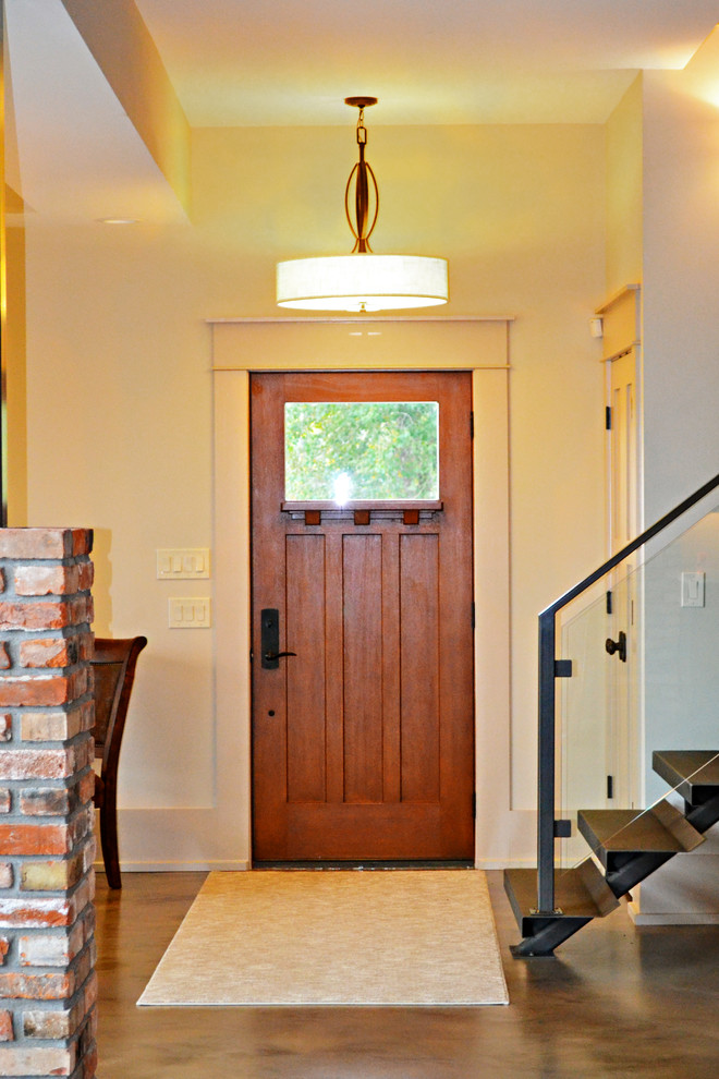 Foto di una grande porta d'ingresso moderna con pareti beige, pavimento in cemento, una porta singola e una porta in legno bruno