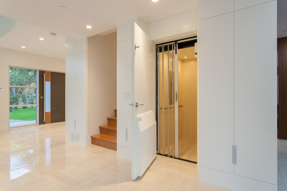 Immagine di una grande porta d'ingresso minimalista con pareti bianche, pavimento in gres porcellanato, una porta singola e una porta marrone