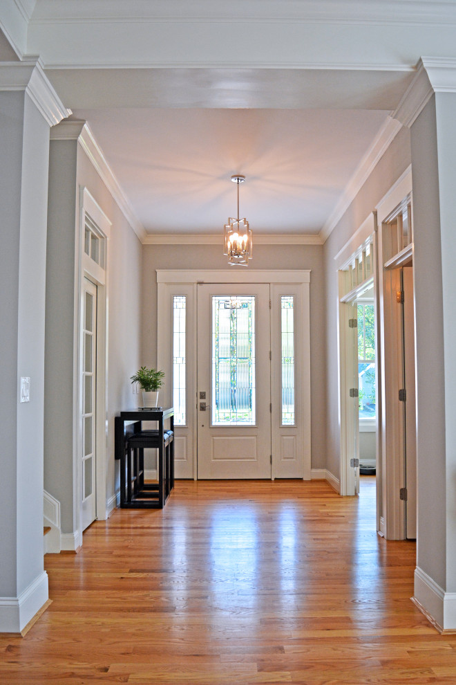 Aménagement d'un hall d'entrée classique avec un mur gris, un sol en bois brun, une porte simple, une porte blanche et un sol marron.