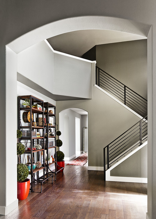 A hallway with a bookcase and stairs. Ceiling grey.
