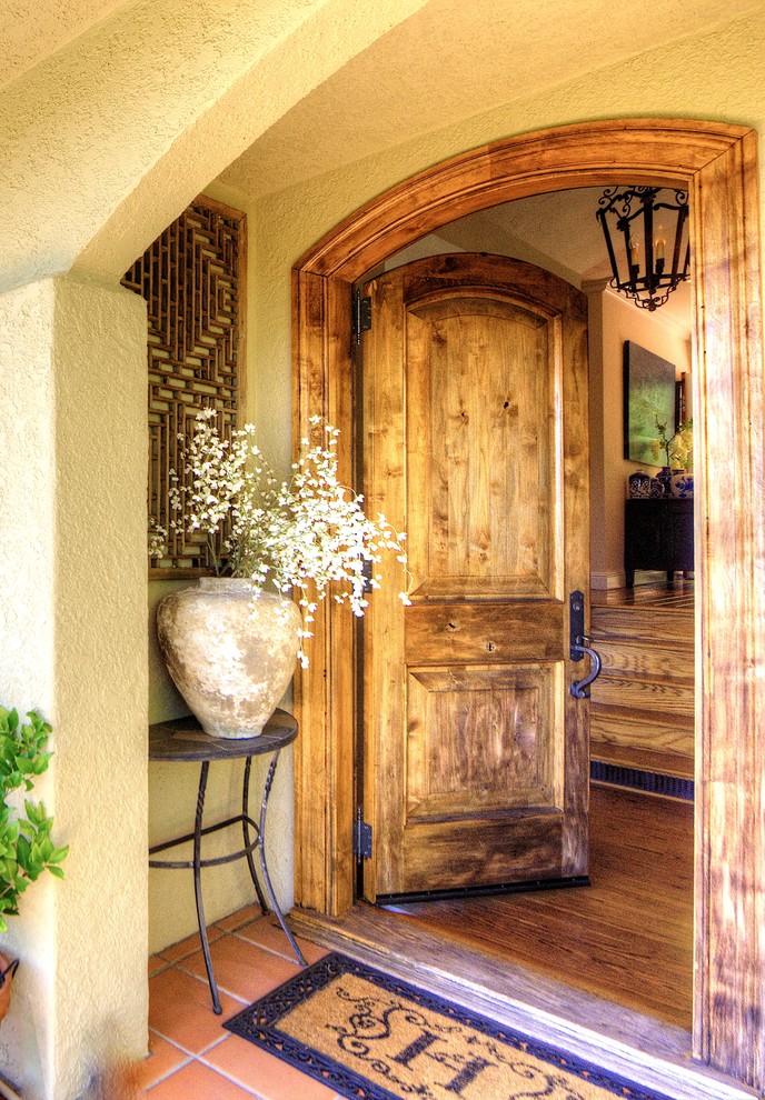 Foto på en stor medelhavsstil ingång och ytterdörr, med beige väggar, mellanmörkt trägolv, en enkeldörr och mellanmörk trädörr