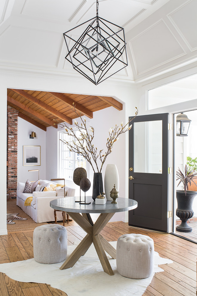 Example of a mid-sized transitional light wood floor and brown floor entryway design in Los Angeles with white walls and a black front door