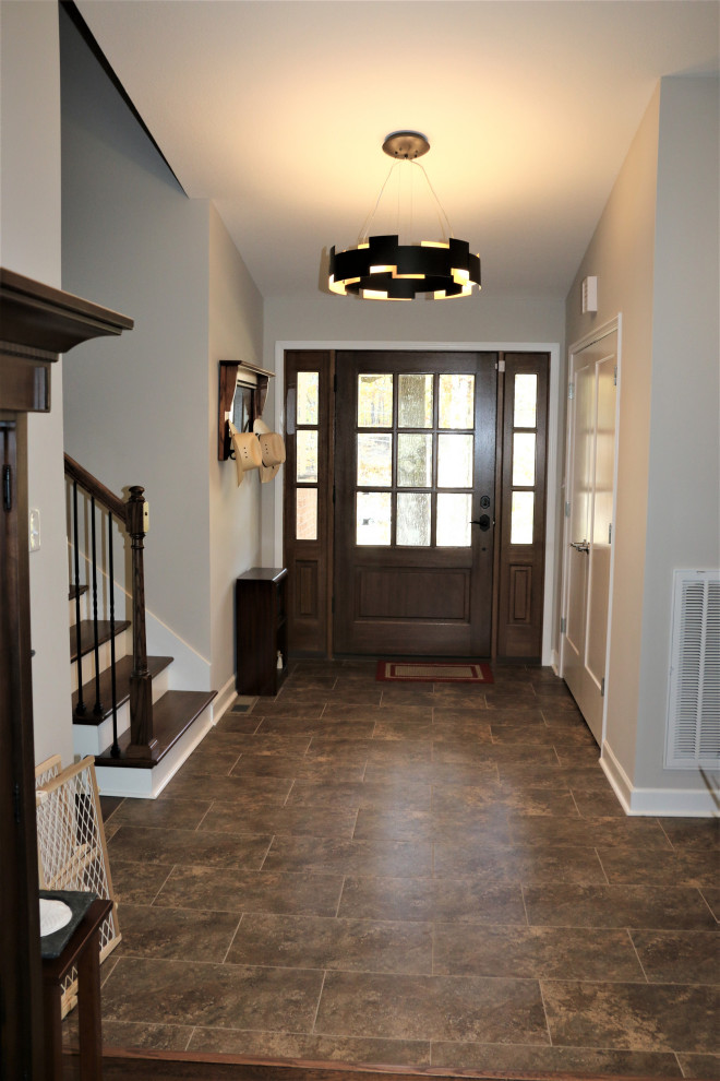 他の地域にある高級な中くらいなトランジショナルスタイルのおしゃれな玄関ドア (グレーの壁、セラミックタイルの床、濃色木目調のドア、茶色い床) の写真