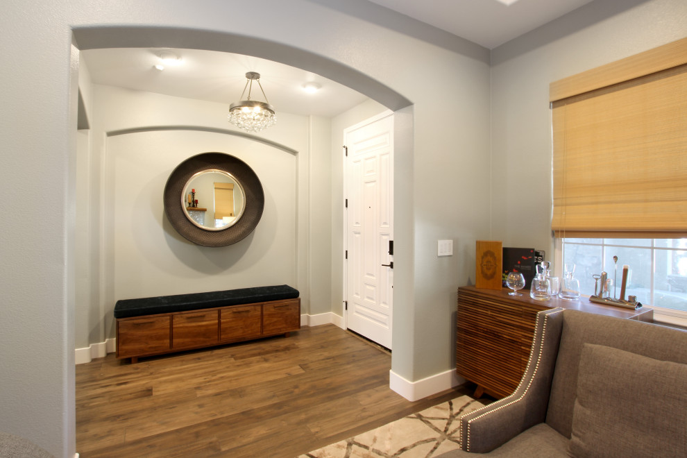 Стильный дизайн: большая узкая прихожая в стиле неоклассика (современная классика) с серыми стенами, паркетным полом среднего тона, одностворчатой входной дверью, белой входной дверью и коричневым полом - последний тренд
