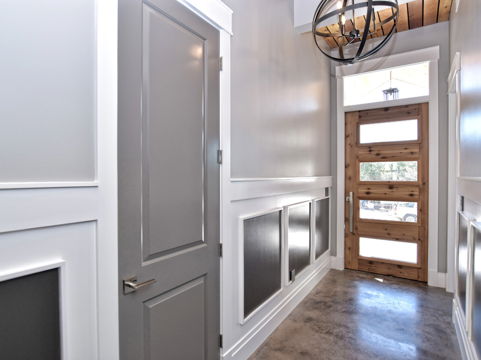 Idée de décoration pour une porte d'entrée tradition de taille moyenne avec un mur gris, sol en béton ciré, une porte simple, une porte grise et un sol marron.