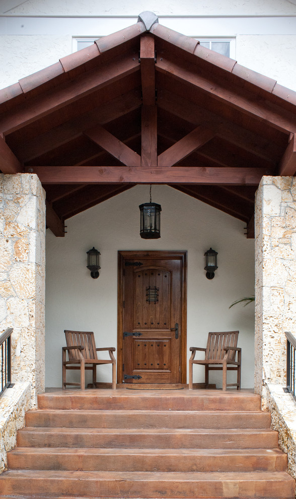 Foto di un'ampia porta d'ingresso tropicale con pareti bianche, pavimento in cemento, una porta singola e una porta in legno bruno