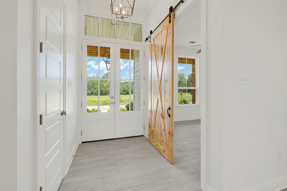Example of a country ceramic tile and gray floor entryway design in New Orleans with gray walls and a white front door