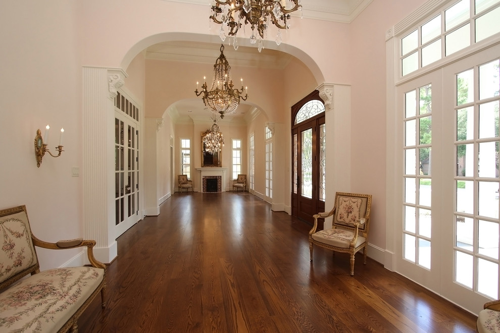 Пример оригинального дизайна: фойе среднего размера в классическом стиле с розовыми стенами, паркетным полом среднего тона, одностворчатой входной дверью и входной дверью из дерева среднего тона