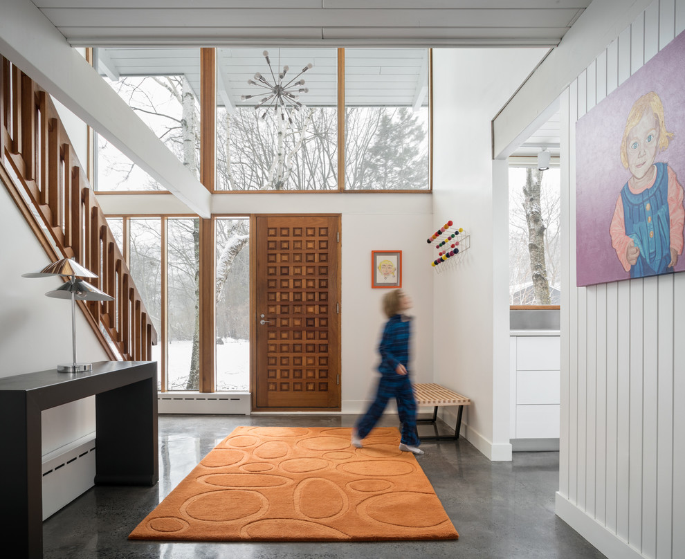 Esempio di un ingresso minimalista con pareti bianche, pavimento in cemento, una porta singola, una porta in legno bruno e pavimento grigio