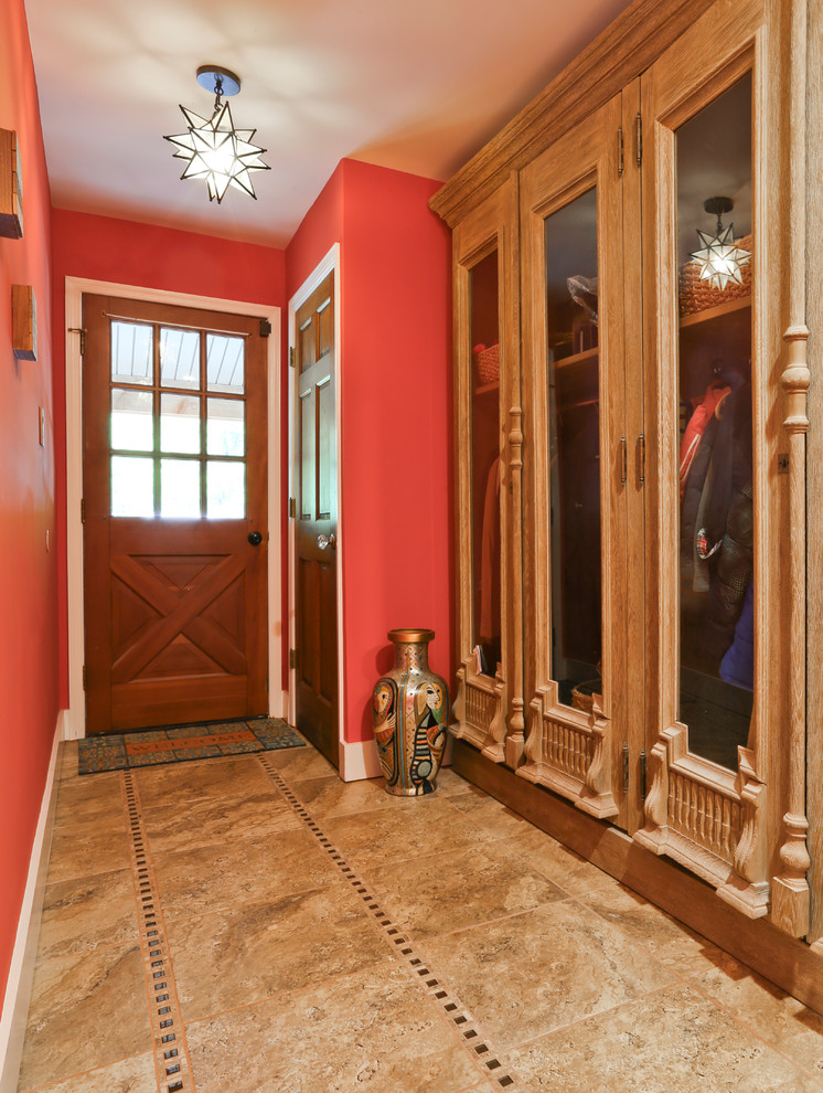 Inredning av ett lantligt mellanstort kapprum, med röda väggar, mörkt trägolv, en enkeldörr, mellanmörk trädörr och beiget golv