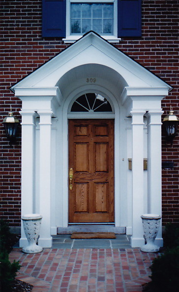 Aménagement d'une grande porte d'entrée classique avec un mur multicolore, un sol en ardoise, une porte simple et une porte en bois brun.