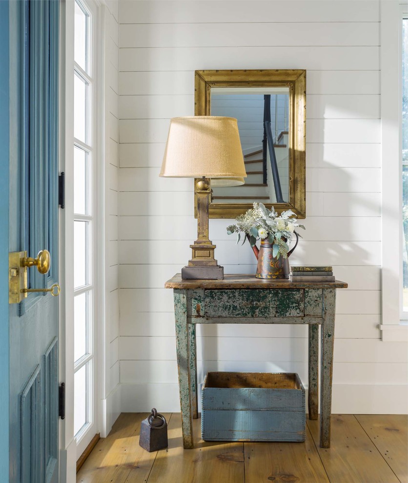 Ispirazione per una porta d'ingresso country con pareti bianche, pavimento in legno massello medio, una porta singola, una porta blu e pavimento marrone