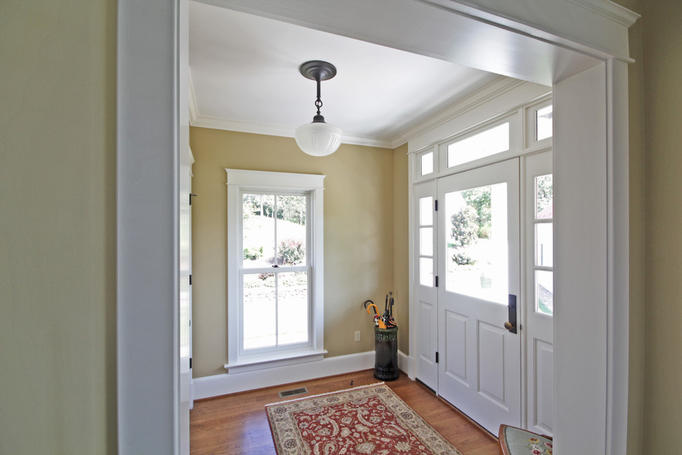 Lantlig inredning av en mellanstor farstu, med beige väggar, mellanmörkt trägolv, en enkeldörr och en vit dörr