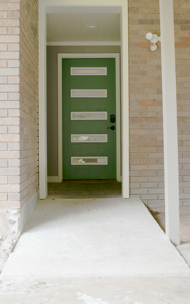 Esempio di una porta d'ingresso moderna con pavimento in cemento, una porta singola e una porta verde