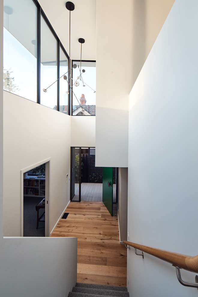 Idee per un ingresso design di medie dimensioni con pareti grigie, parquet chiaro, una porta a pivot e una porta verde