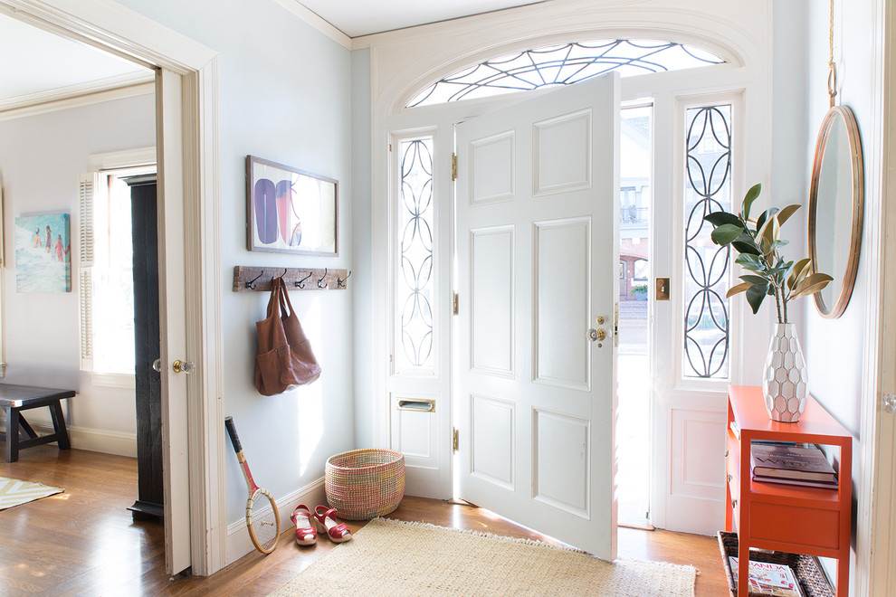Réalisation d'une entrée tradition de taille moyenne avec un mur gris, un sol en bois brun, une porte simple et une porte blanche.