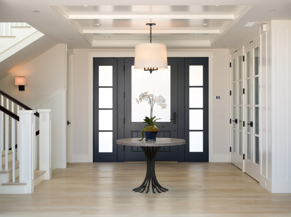 サンディエゴにある広いトランジショナルスタイルのおしゃれな玄関ロビー (淡色無垢フローリング、黒いドア、白い壁、ベージュの床) の写真