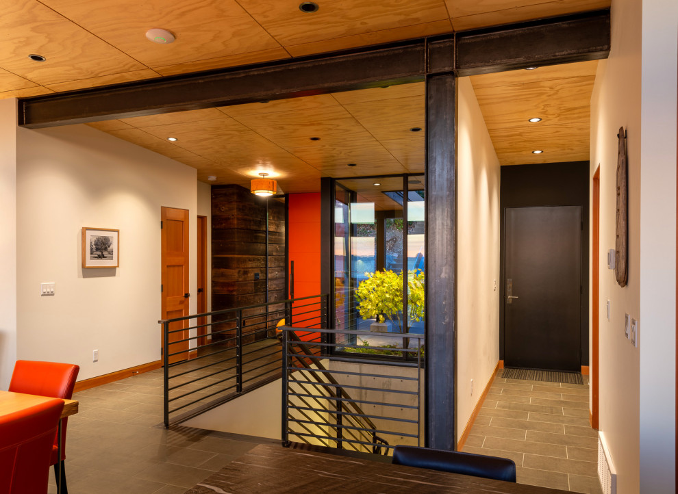 Пример оригинального дизайна: входная дверь среднего размера в стиле модернизм с коричневыми стенами, полом из керамогранита, одностворчатой входной дверью, оранжевой входной дверью и серым полом