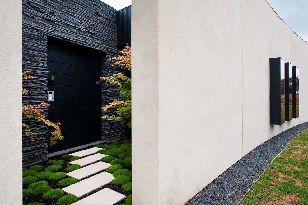 Idee per un ampio ingresso o corridoio contemporaneo con pareti beige, una porta a pivot e una porta nera