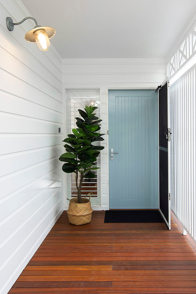 Idee per una porta d'ingresso costiera di medie dimensioni con pareti bianche, pavimento in legno massello medio, una porta singola, una porta blu e pavimento marrone