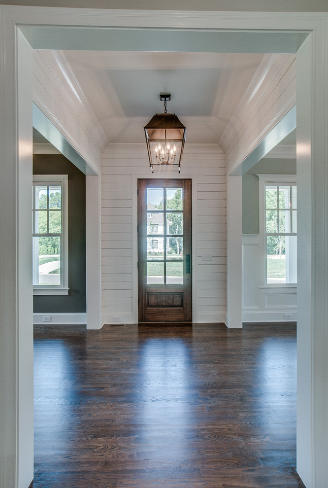 Exemple d'une grande porte d'entrée chic avec un mur blanc, parquet foncé, une porte simple et une porte en bois foncé.