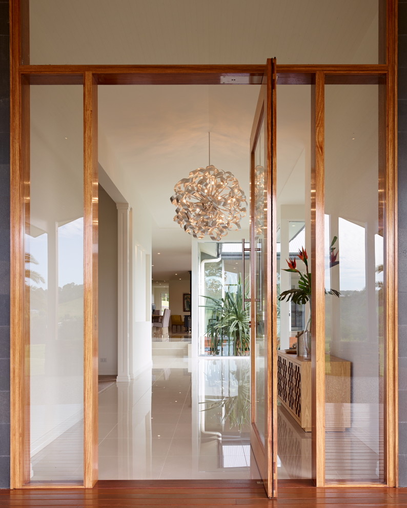 Idee per un'ampia porta d'ingresso minimalista con pareti bianche, una porta a pivot e una porta in legno bruno