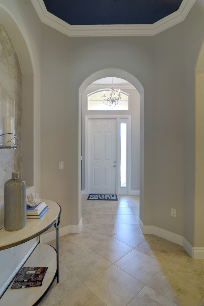 Cette image montre un vestibule design avec un mur beige, un sol en carrelage de céramique, une porte simple et une porte blanche.