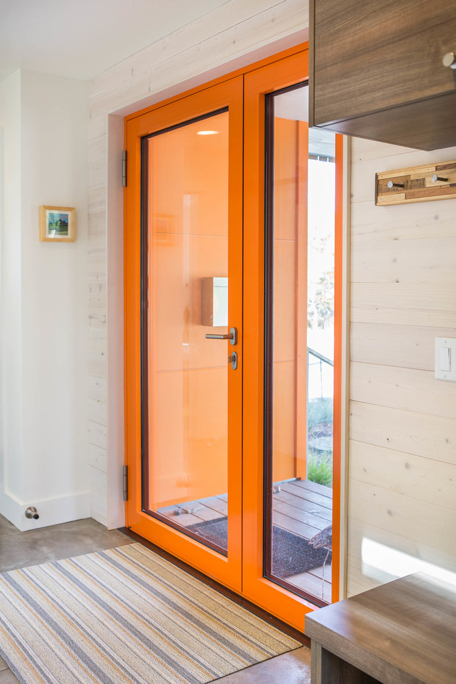 Idee per una piccola porta d'ingresso minimal con pareti bianche, pavimento in cemento, una porta singola, una porta arancione e pavimento grigio