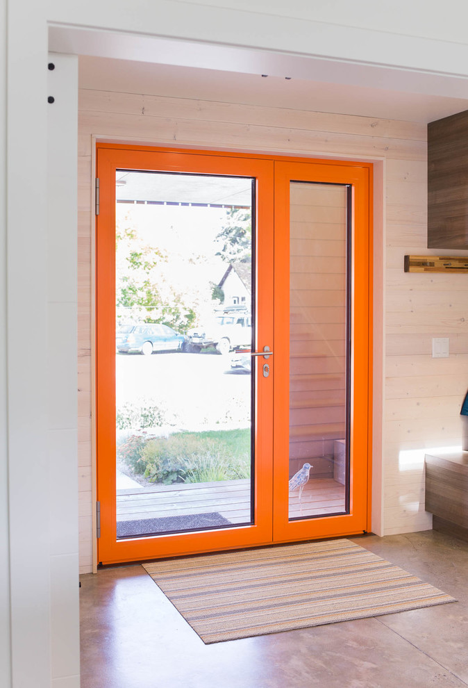 Inspiration för en liten funkis ingång och ytterdörr, med vita väggar, betonggolv, en enkeldörr, en orange dörr och grått golv