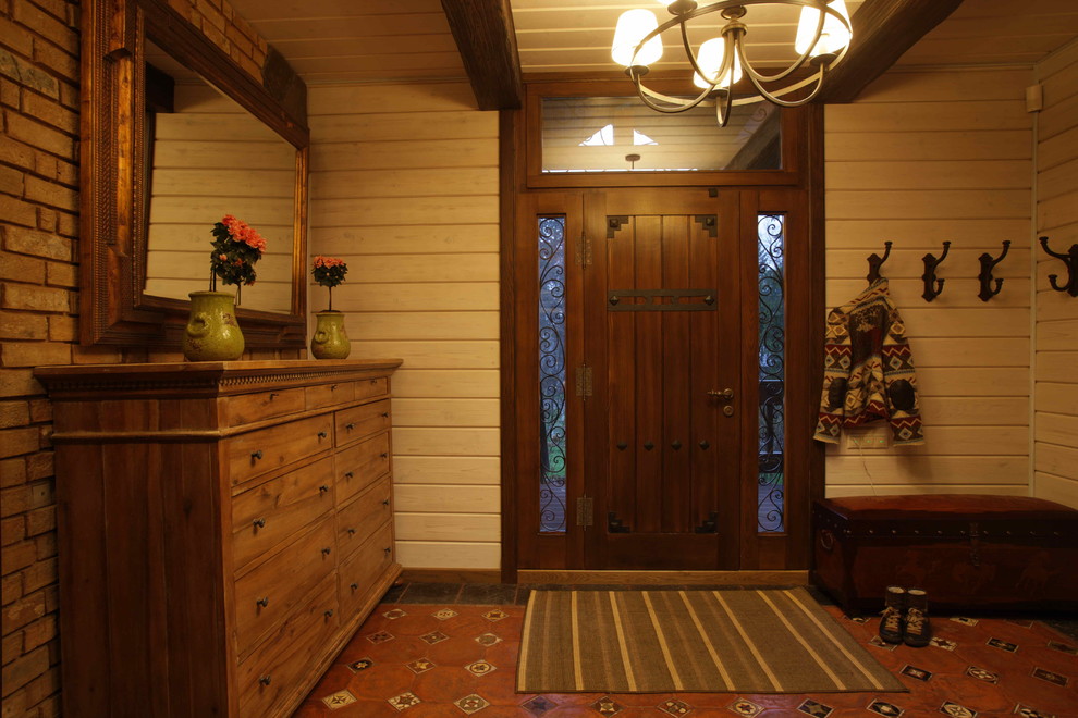 Ejemplo de distribuidor campestre de tamaño medio con paredes blancas, suelo de baldosas de terracota, puerta simple y puerta marrón