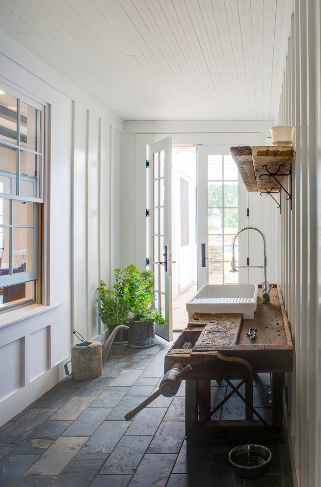 Example of a farmhouse slate floor entryway design in DC Metro with white walls and a glass front door