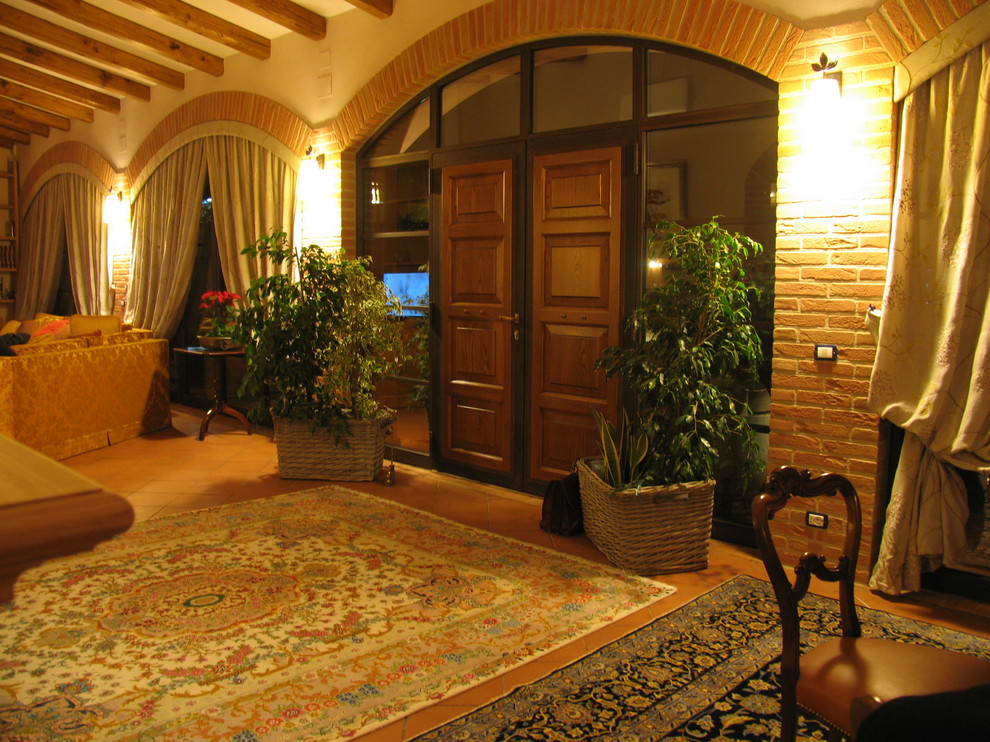 Cette photo montre un grand hall d'entrée chic avec un mur beige, tomettes au sol, une porte double et une porte en bois brun.