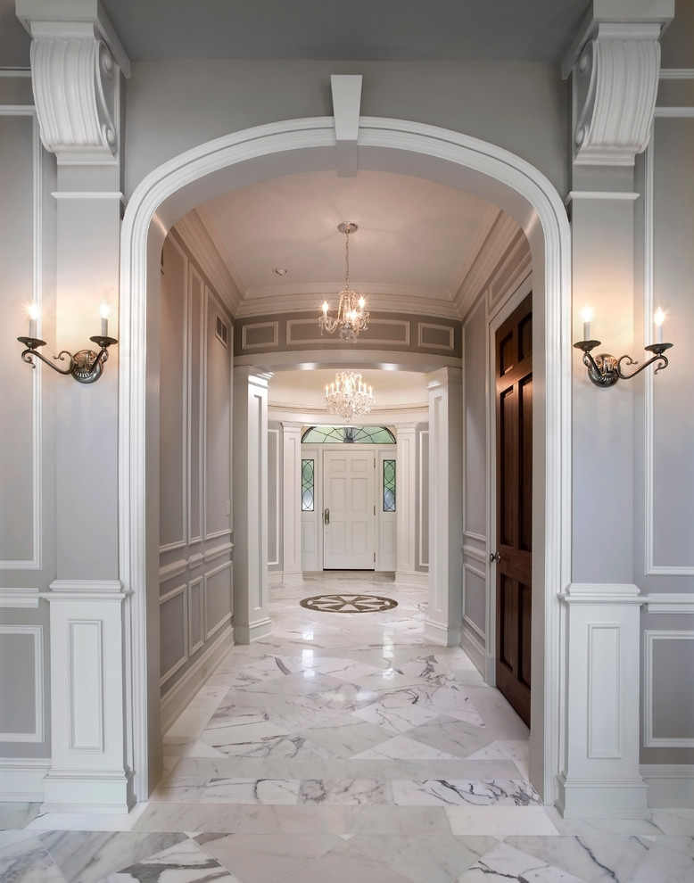 Réalisation d'une entrée tradition avec un mur gris, une porte simple, une porte blanche et un sol en marbre.