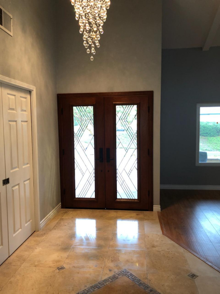 Inspiration for a large contemporary front door in Orange County with grey walls, limestone flooring, a double front door, a medium wood front door and beige floors.