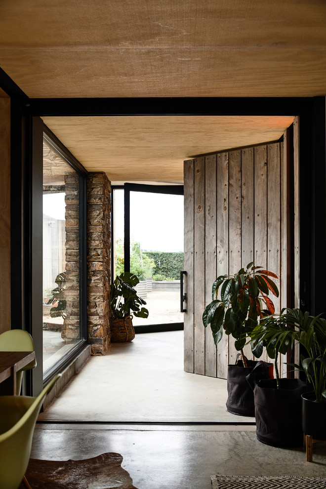 Idée de décoration pour une entrée design avec un couloir, une porte simple, une porte en bois brun et un sol gris.