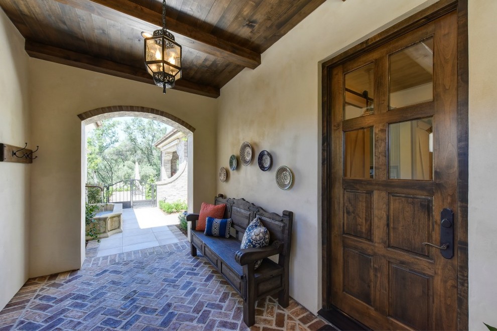 Geräumige Mediterrane Haustür mit beiger Wandfarbe, Backsteinboden, Einzeltür, dunkler Holzhaustür und braunem Boden in Sacramento