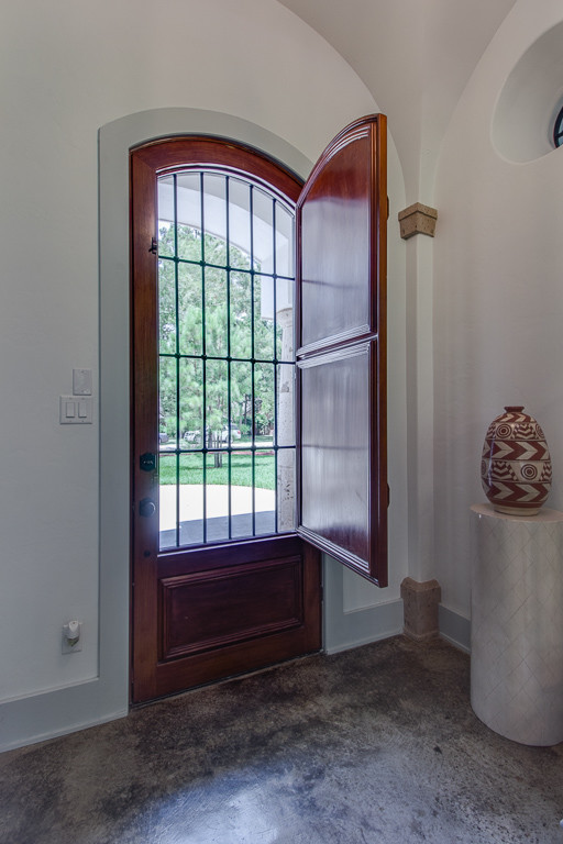 Uriges Foyer mit weißer Wandfarbe, Betonboden, Einzeltür und hellbrauner Holzhaustür in Houston