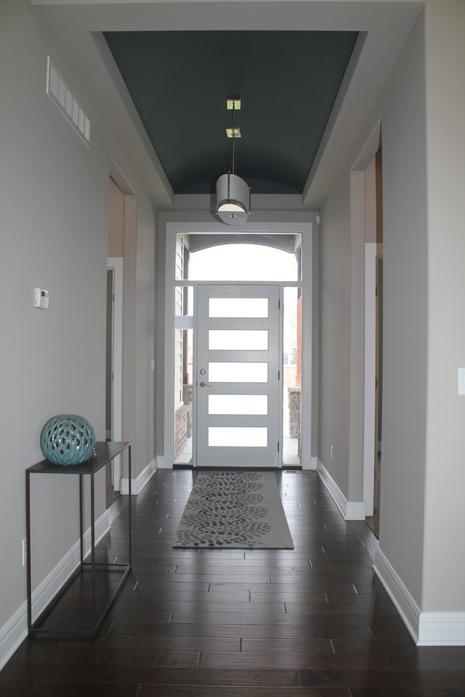 Réalisation d'une entrée tradition de taille moyenne avec un couloir, un mur gris, parquet foncé, une porte simple et une porte blanche.