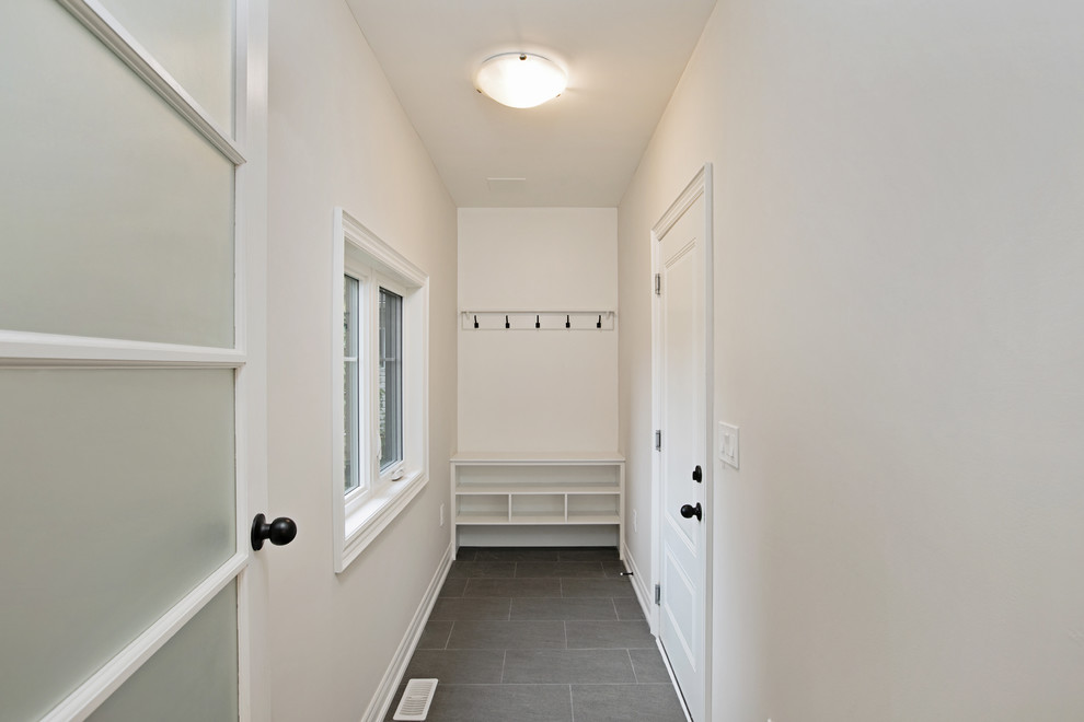Cette image montre une petite entrée traditionnelle avec un vestiaire, un mur blanc, un sol en carrelage de céramique, une porte simple, une porte grise et un sol gris.
