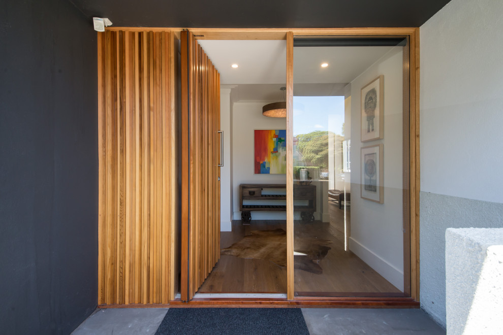 Geräumige Maritime Haustür mit grauer Wandfarbe, Betonboden, Drehtür, hellbrauner Holzhaustür und grauem Boden in Melbourne