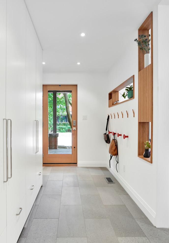トロントにあるラグジュアリーな中くらいなコンテンポラリースタイルのおしゃれな玄関ロビー (白い壁、ガラスドア、グレーの床) の写真